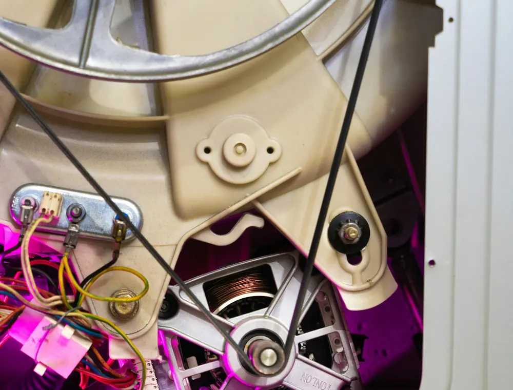 Motor y correa de arrastre de un electrodoméstico abierto durante la reparación